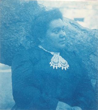 woman sits next to tree wearing a 19th century dress with lace necklace