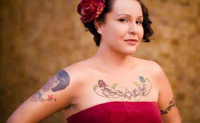 a tattooed woman in a red dress wearing a rose in her hair