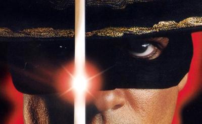 Close-up of a person's face wearing a black mask and hat with gold trim, divided by a bright, glowing sword. One intense eye and part of the hat are vividly visible against a red background.