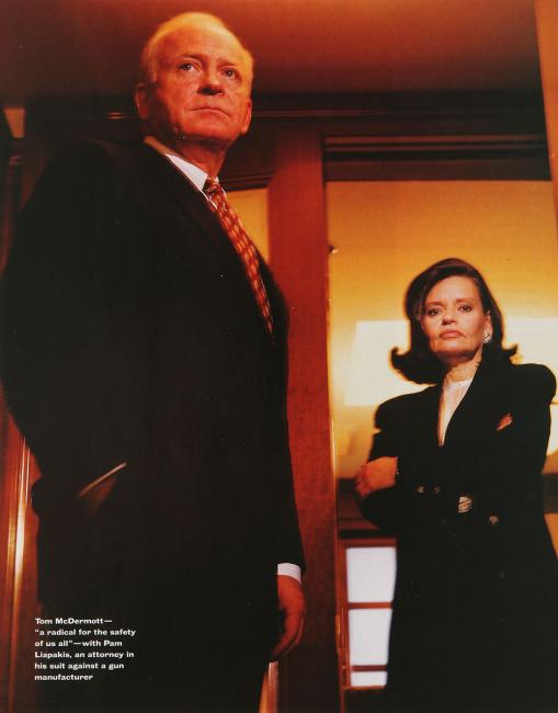 Man and woman in suits, the woman stands and the door to the office, both look toward the viewer