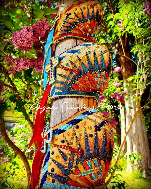 a series of beaded masks wrapped around a wooden pole