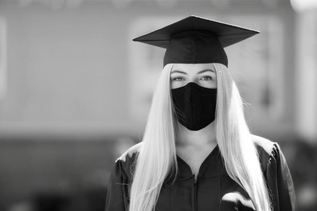 a student wears a mask with her graduation clothing