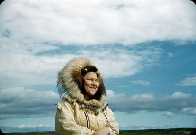woman in heavy winter coat stands with sky in background