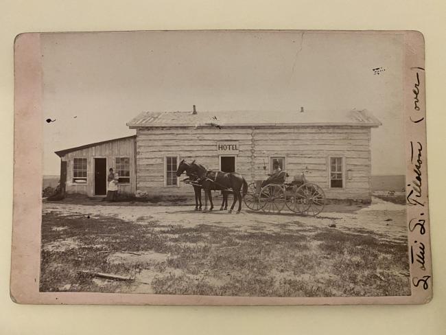 photograph printed on card of horses and buggy in front of an old hotel