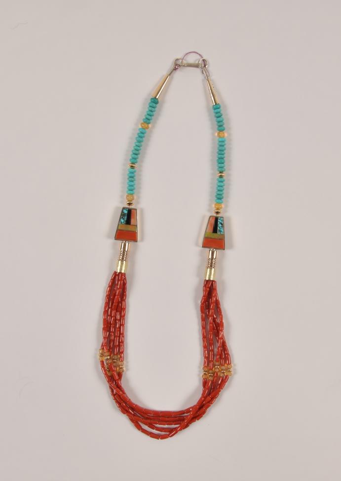 A necklace with two strands of small red beads, turquoise beads near the clasp, and two triangular pendants featuring turquoise and orange inlay. The necklace has silver accents and a metal hook clasp.