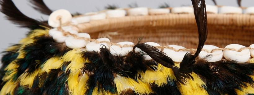 close-up of a basket with feathers and shells woven into it
