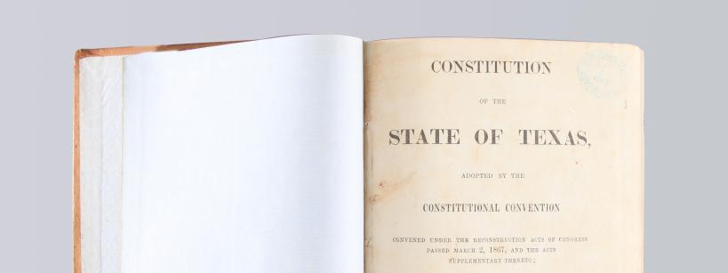 open book with the title "Constitution of the State of Texas"