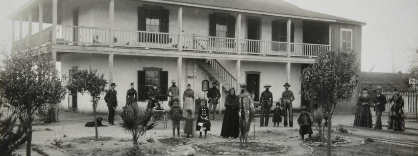 black and white photograph of a family standing in front of a white two-story building