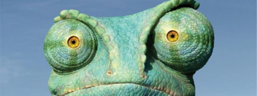 A quirky, big-eyed chameleon wearing a red Hawaiian shirt stands in a desert with cacti. The text reads “Johnny Depp is Rango.” The sky is clear and blue.