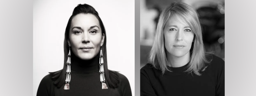 Black and white photo of two women in dark tops; the woman on the left wears long beaded earrings, while the woman on the right has shoulder-length hair. Both face the camera with neutral expressions.
