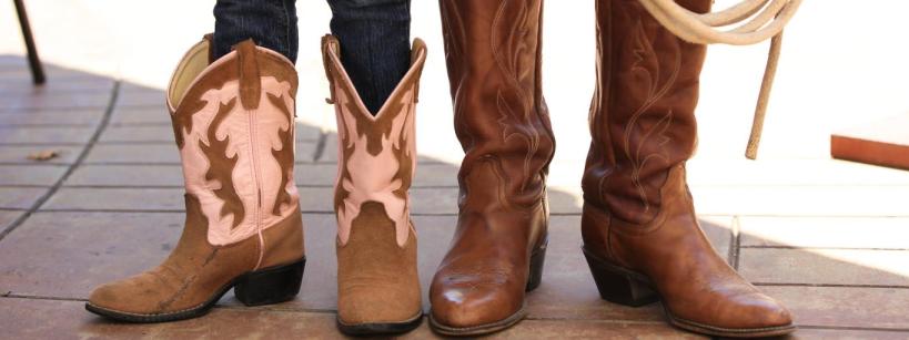 A pair of brown and pink cowboy boots standing next to a pair of brown leather cowboy boots.