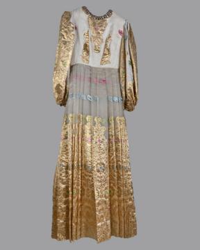 A long vintage dress with a high neckline and full sleeves. The upper part is white with ornate gold embroidery, while the skirt features golden patterns and floral accents on sheer fabric. The dress has a regal, elegant style.