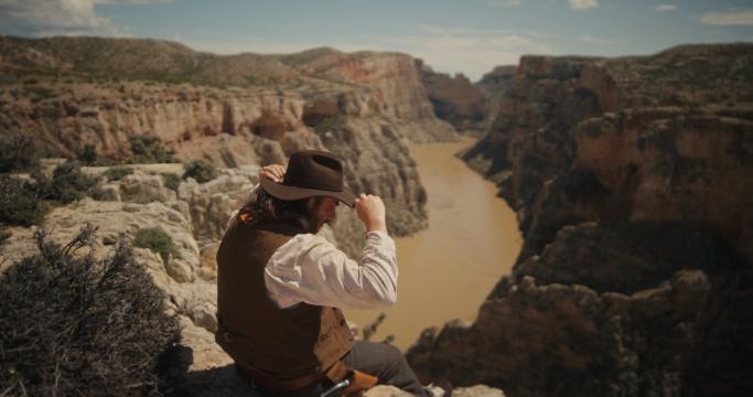 A man sitting on a rock looking at a river.