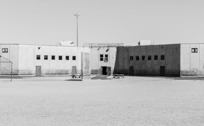 a prison. a lone security guard is in a doorway