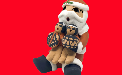 A clay figurine of Santa Claus holding two small figures painted with geometric patterns.