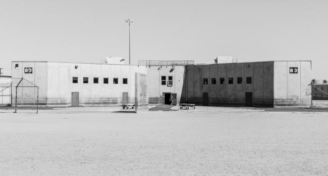 a prison. a lone security guard is in a doorway