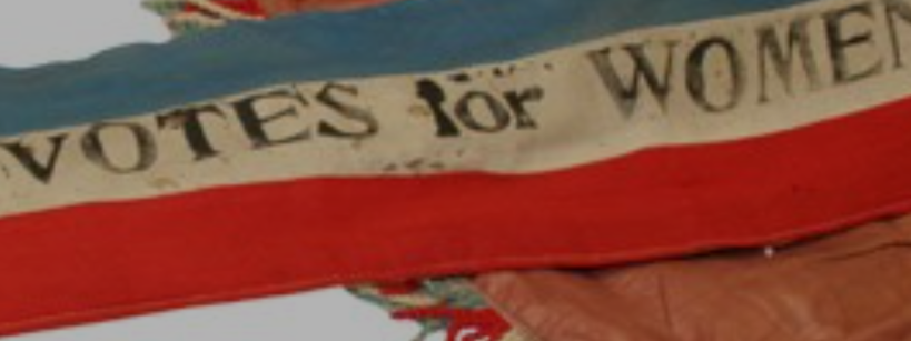 red, white, and blue banner with text saying "VOTES FOR WOMEN"