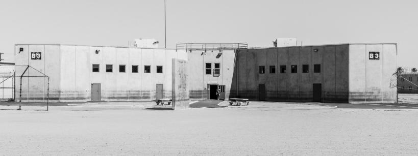 a prison. a lone security guard is in a doorway