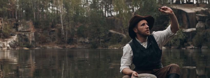 prospector inspects nugget in body of water